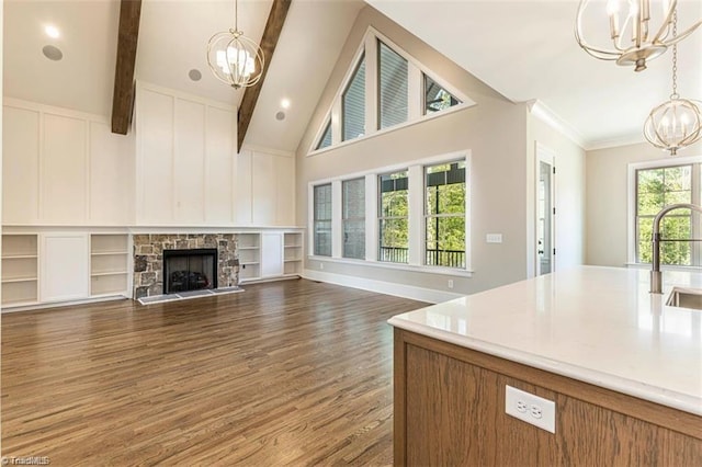 unfurnished living room featuring a stone fireplace, high vaulted ceiling, dark hardwood / wood-style floors, a notable chandelier, and beamed ceiling