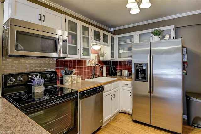 kitchen featuring light countertops, backsplash, appliances with stainless steel finishes, and a sink