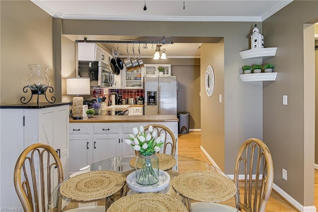 dining room featuring baseboards, light wood-style floors, and crown molding