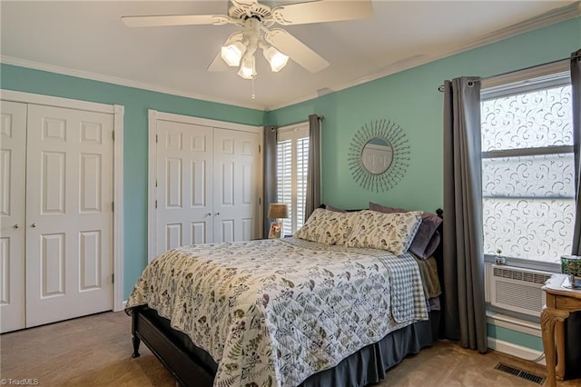 bedroom featuring carpet flooring, crown molding, and multiple closets