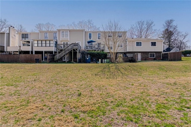 back of property with a lawn and fence