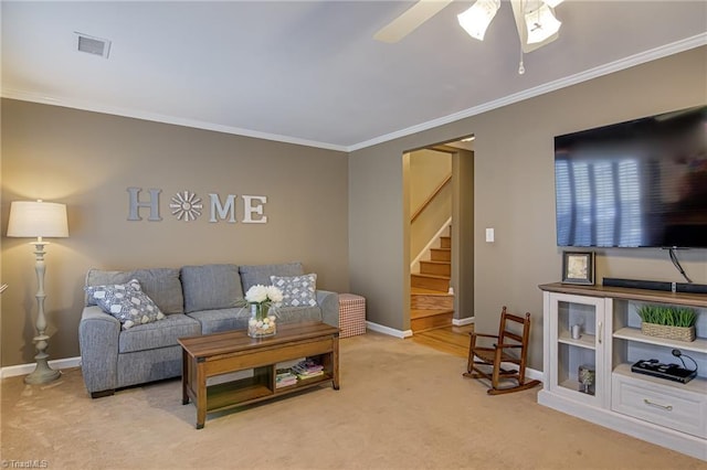 living room with ornamental molding, baseboards, light colored carpet, ceiling fan, and stairs