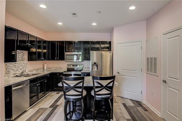 6801 Hanesbrook Cir Unit 104, Clemmons, NC 27012 - kitchen with stainless steel appliances, dark cabinets, a sink, light wood-type flooring, and recessed lighting