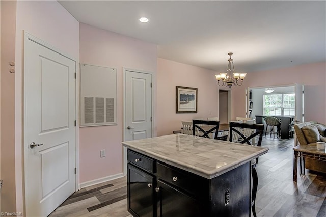 6801 Hanesbrook Cir Unit 104, Clemmons, NC 27012 - kitchen with dark cabinetry, a chandelier, light wood-style floors, open floor plan, and pendant lighting