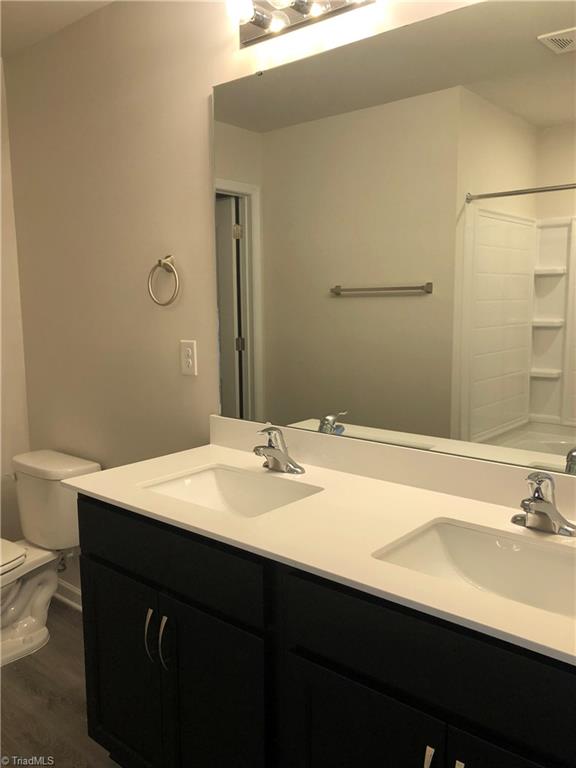 2866 Tysinger Rd, Denton, NC 27239 - bathroom with double vanity, toilet, wood finished floors, and shower / bath combination