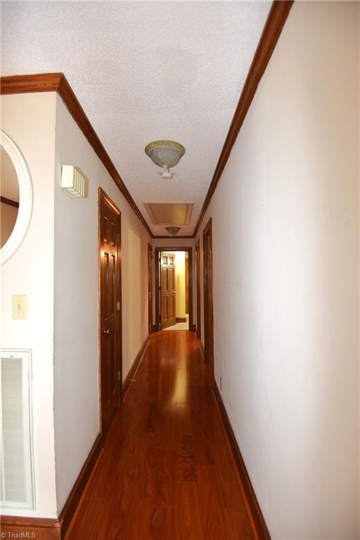 hall with a textured ceiling, hardwood / wood-style flooring, and ornamental molding