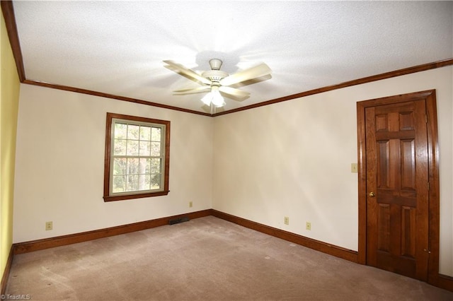 empty room featuring light carpet, a textured ceiling, ceiling fan, and crown molding