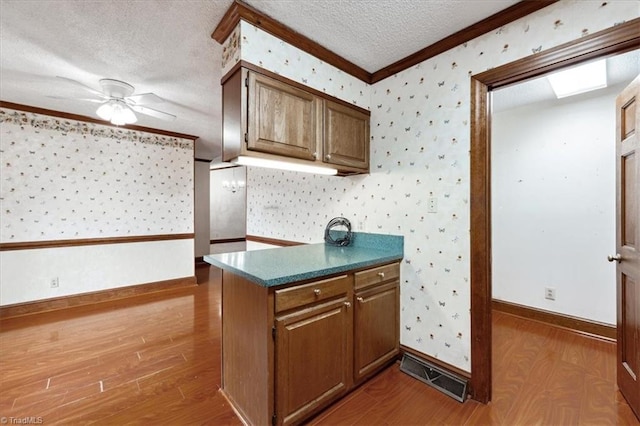 206 Swaim Ct, Salisbury, NC 28147 - kitchen featuring ornamental molding, wood finished floors, wallpapered walls, a ceiling fan, and dark countertops