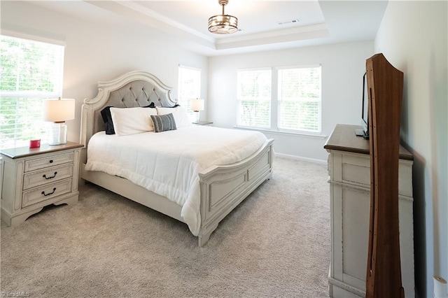 bedroom featuring a tray ceiling, light colored carpet, baseboards, and visible vents