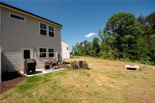 rear view of property featuring central air condition unit, a patio area, an outdoor fire pit, and a lawn