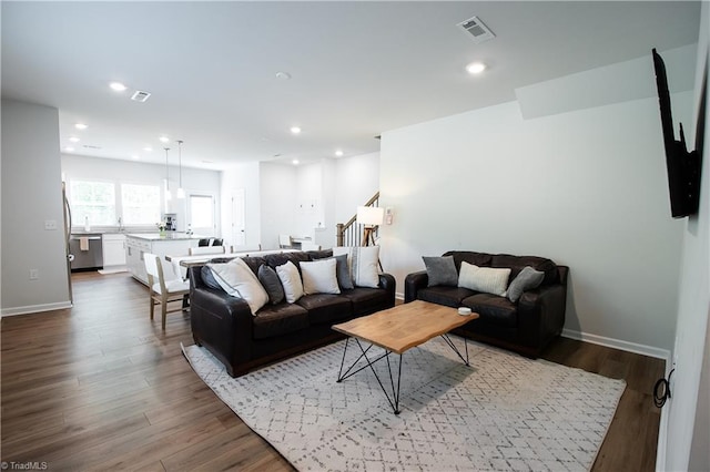 living room with stairs, dark wood-type flooring, visible vents, and recessed lighting