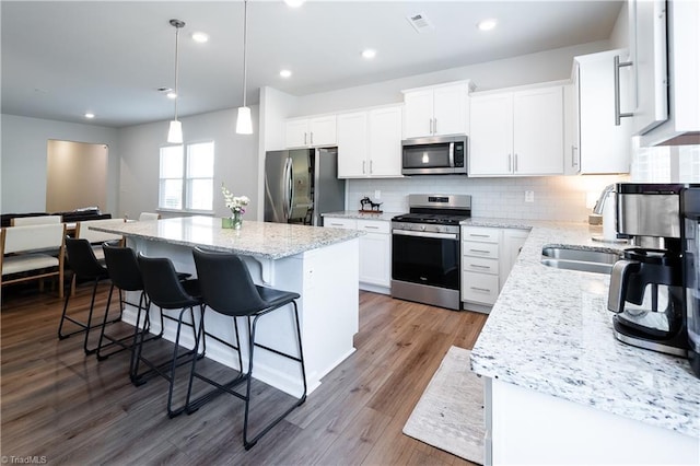 kitchen featuring a breakfast bar area, a center island, stainless steel appliances, white cabinetry, and tasteful backsplash