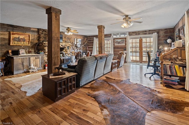 living room with ceiling fan, french doors, light hardwood / wood-style flooring, and decorative columns