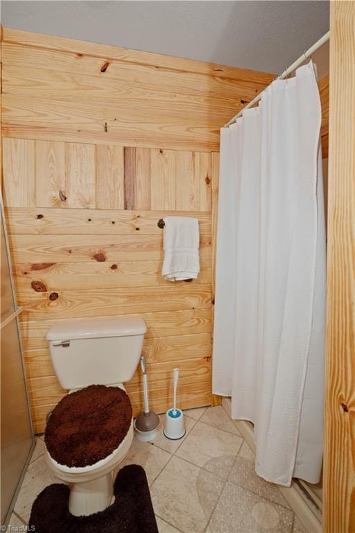 bathroom featuring tile patterned floors, toilet, and wooden walls