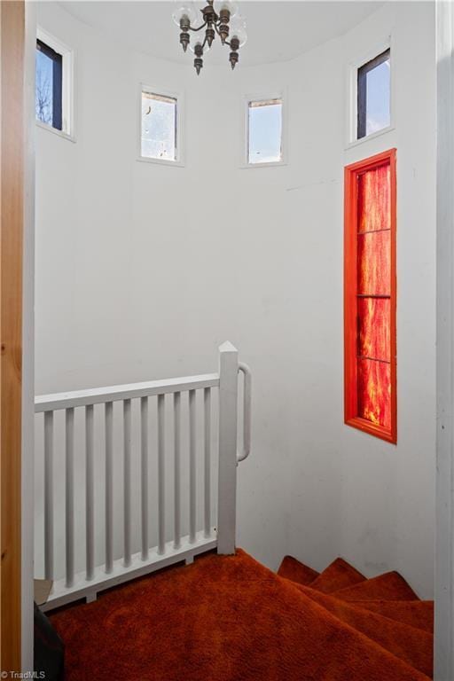 stairway featuring carpet flooring, radiator, and a chandelier