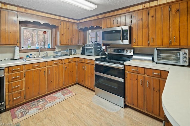 kitchen featuring a textured ceiling, light hardwood / wood-style floors, sink, and stainless steel appliances