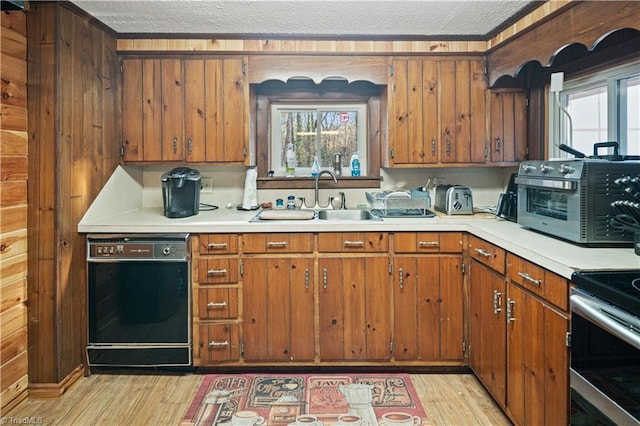 kitchen with a textured ceiling, sink, light hardwood / wood-style floors, stainless steel electric range oven, and wood walls