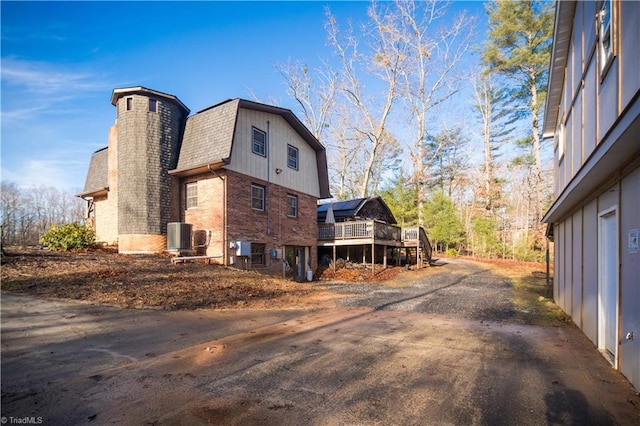 view of side of property featuring a wooden deck and central AC unit