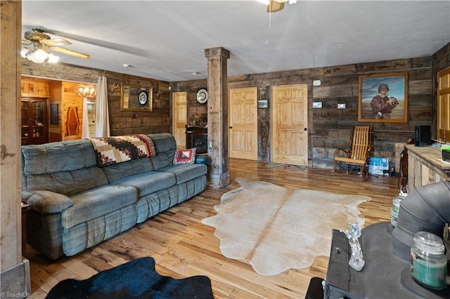 living room with ornate columns, wooden walls, ceiling fan, and light wood-type flooring