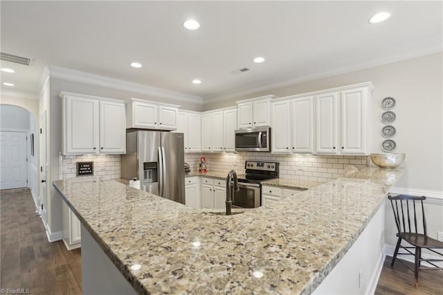 kitchen featuring light stone counters, stainless steel appliances, arched walkways, and visible vents