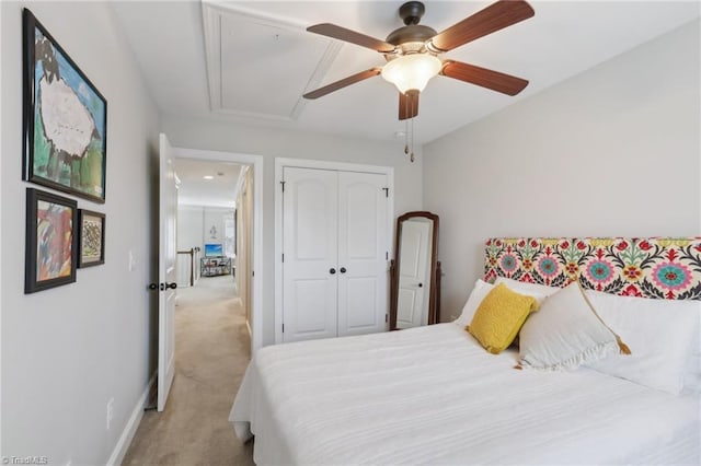 carpeted bedroom with a ceiling fan, attic access, baseboards, and a closet