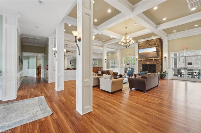 living area featuring beamed ceiling, decorative columns, visible vents, and a decorative wall