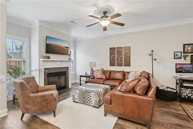 living room featuring visible vents, ornamental molding, a fireplace, wood finished floors, and a ceiling fan