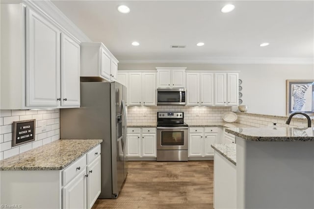 kitchen featuring visible vents, crown molding, a peninsula, white cabinets, and stainless steel appliances