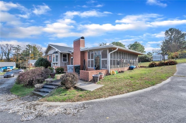 view of front of property featuring a front yard and a sunroom