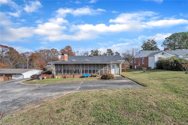 back of property featuring a sunroom and a lawn