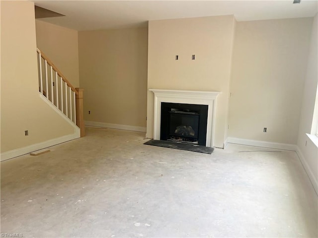 unfurnished living room with stairs, a fireplace, baseboards, and concrete floors