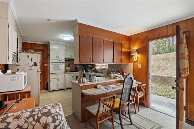 kitchen with light floors, white appliances, a peninsula, and ornamental molding