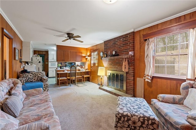 living room with a brick fireplace, light colored carpet, wood walls, and ornamental molding