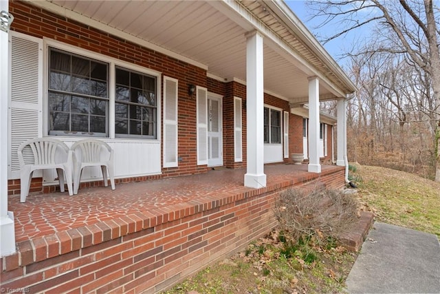 doorway to property featuring brick siding and a porch