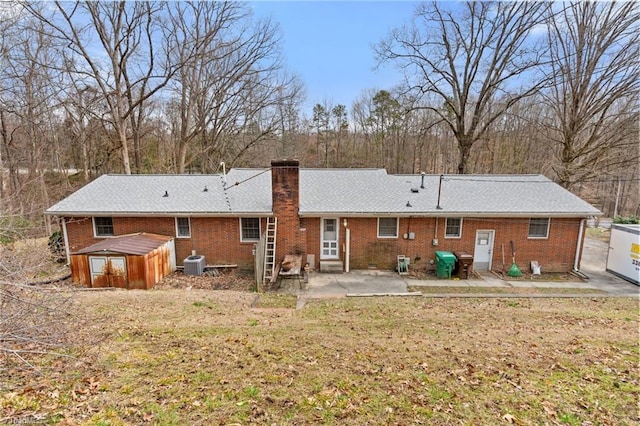 back of property with a patio, brick siding, central AC unit, and a chimney