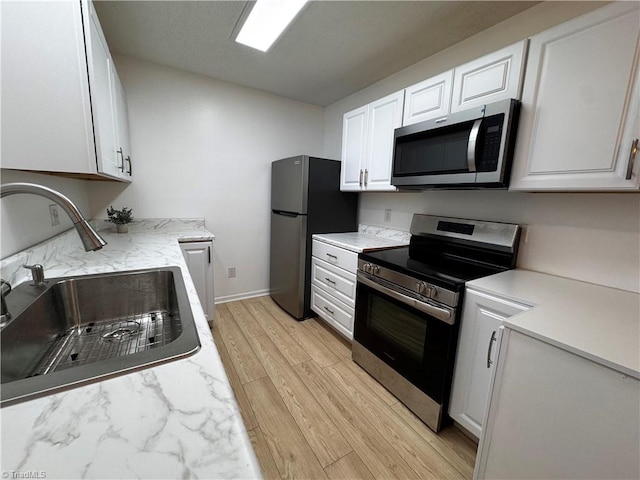 kitchen featuring sink, white cabinetry, stainless steel appliances, and light hardwood / wood-style flooring