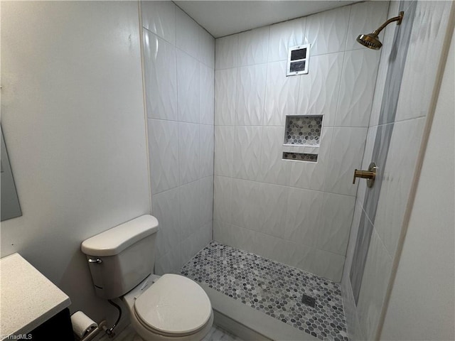 bathroom featuring vanity, toilet, and a tile shower