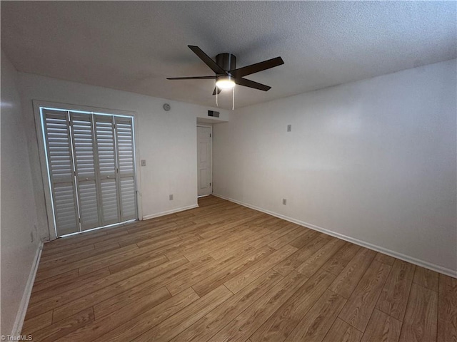 unfurnished bedroom with ceiling fan, a closet, light hardwood / wood-style floors, and a textured ceiling