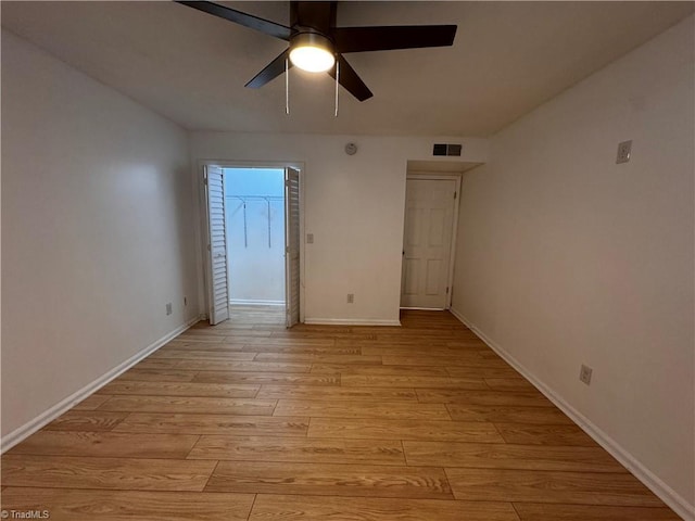 unfurnished bedroom with a closet, light hardwood / wood-style floors, a spacious closet, and ceiling fan