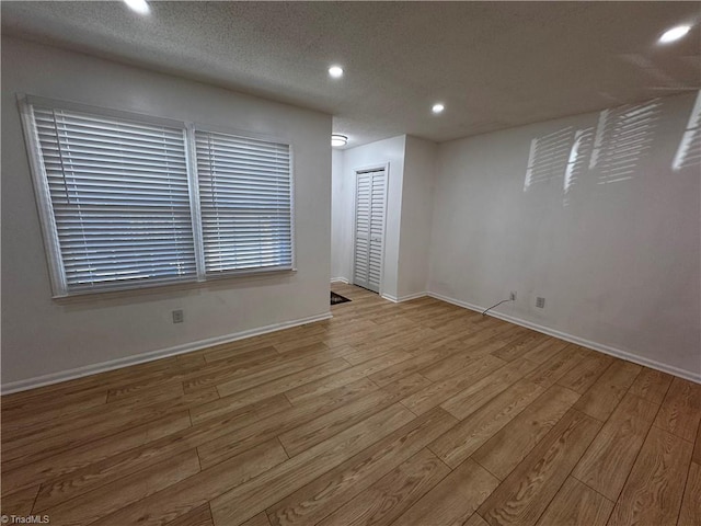 unfurnished room featuring a textured ceiling and light wood-type flooring