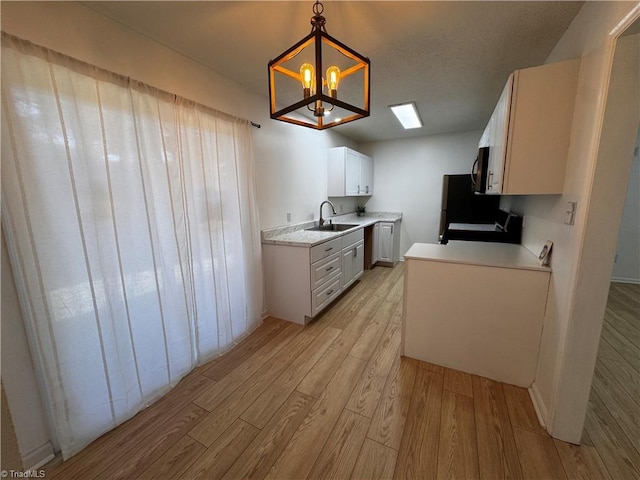 kitchen featuring pendant lighting, light wood-type flooring, white cabinetry, and an inviting chandelier