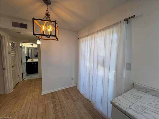 unfurnished dining area with a notable chandelier and light hardwood / wood-style flooring