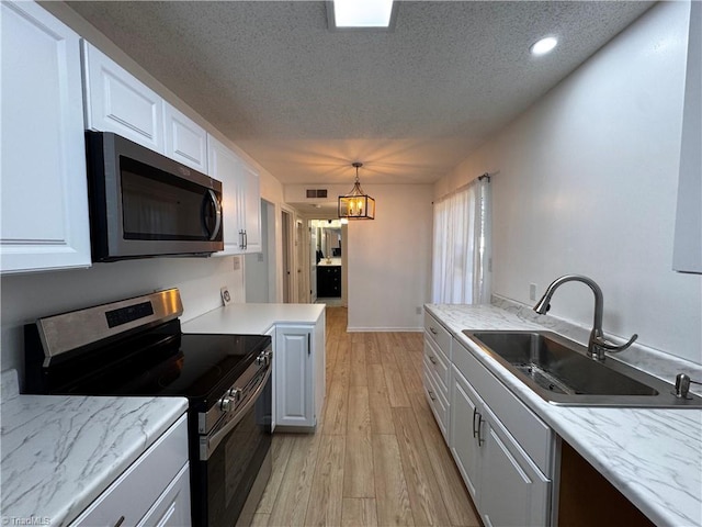 kitchen featuring white cabinets, sink, light hardwood / wood-style flooring, decorative light fixtures, and stainless steel appliances