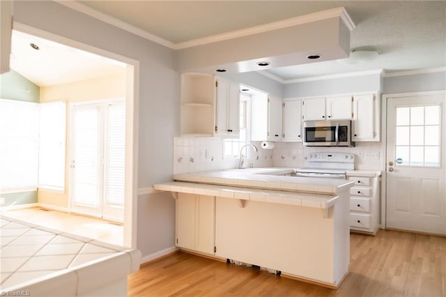 kitchen with tile countertops, kitchen peninsula, white cabinets, and white electric range oven