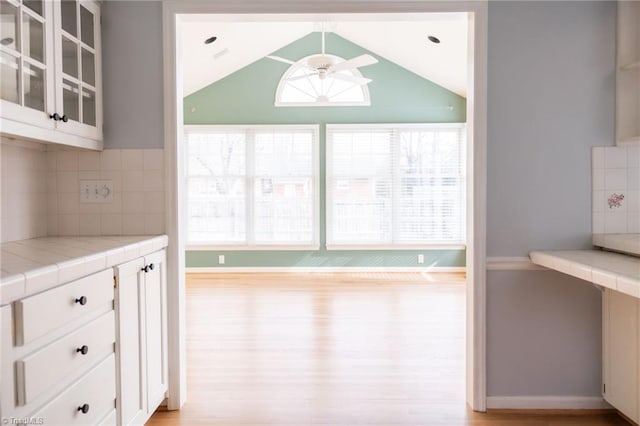 kitchen featuring ceiling fan, tile counters, and white cabinets