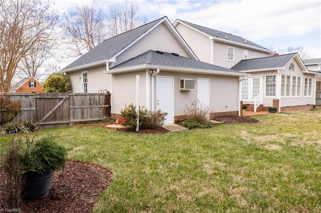 rear view of house with a sunroom, a yard, and a wall mounted air conditioner