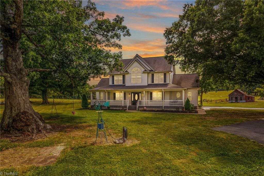 farmhouse with covered porch and a yard