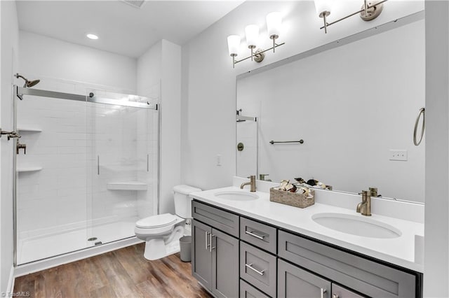 bathroom with hardwood / wood-style floors, vanity, toilet, and a shower with shower door