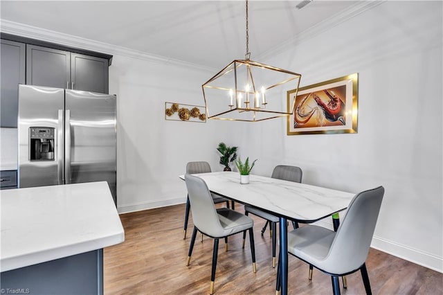 dining space with a chandelier, dark wood-type flooring, and ornamental molding