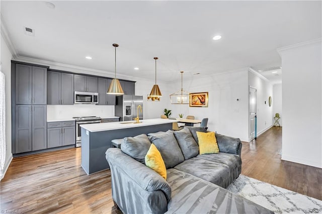 living room with crown molding, hardwood / wood-style floors, an inviting chandelier, and sink